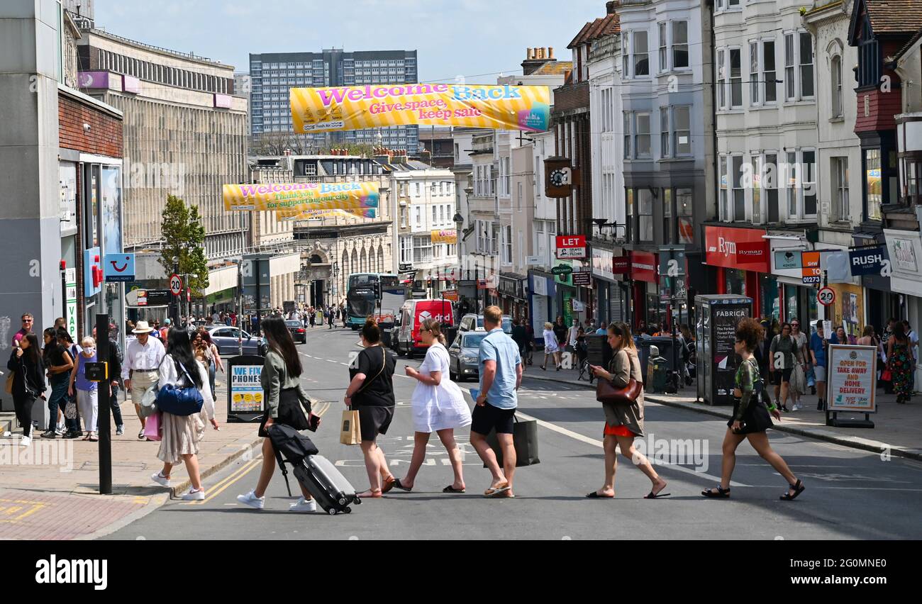 Brighton UK 2nd June 2021 - Visitors walk under a Welcome Back sign in Brighton on another hot day on as the warm weather continues in parts of the UK : Credit Simon Dack / Alamy Live News Stock Photo