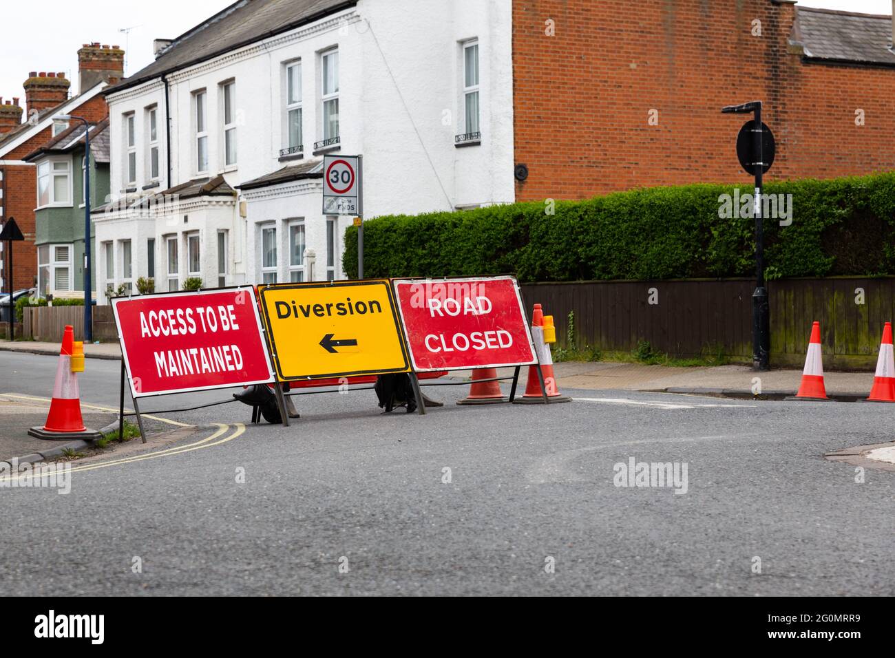 Traffic signs informing the public that the road is closed ahead and to follow the diversion Stock Photo