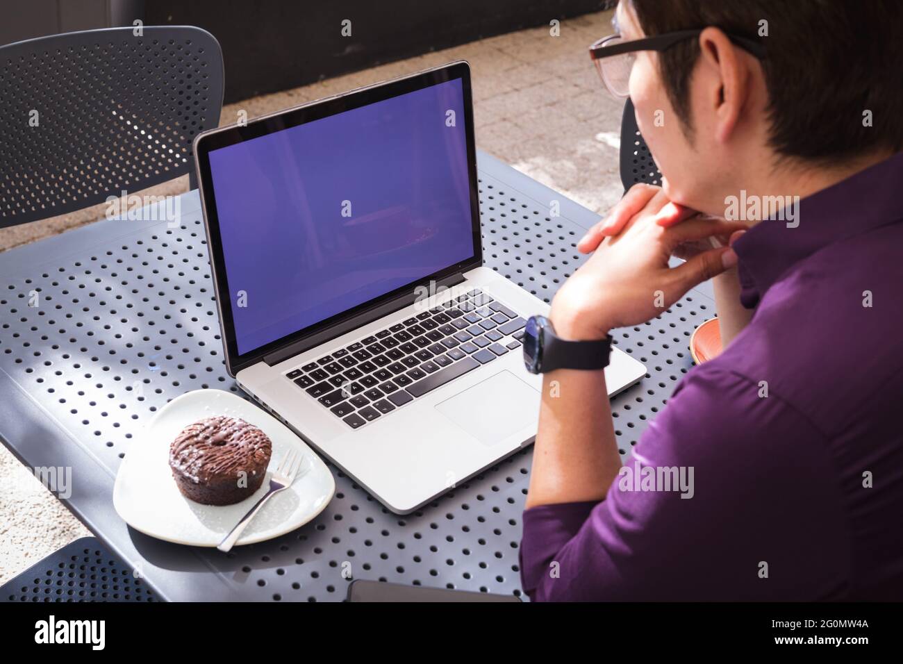 Asian businessman using laptop with blank screen sitting at table in cafe Stock Photo