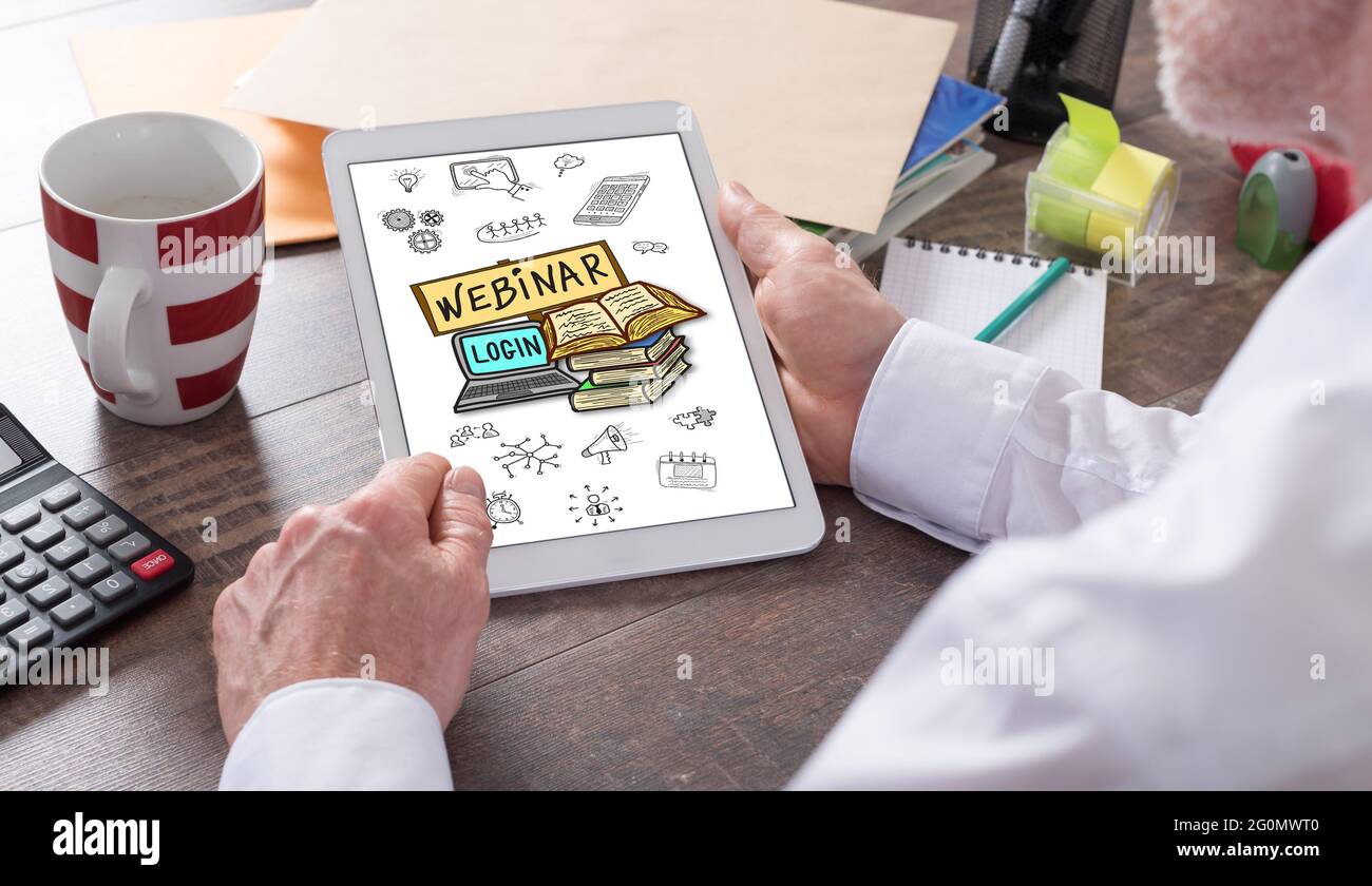 Webinar concept shown on a tablet held by a man Stock Photo