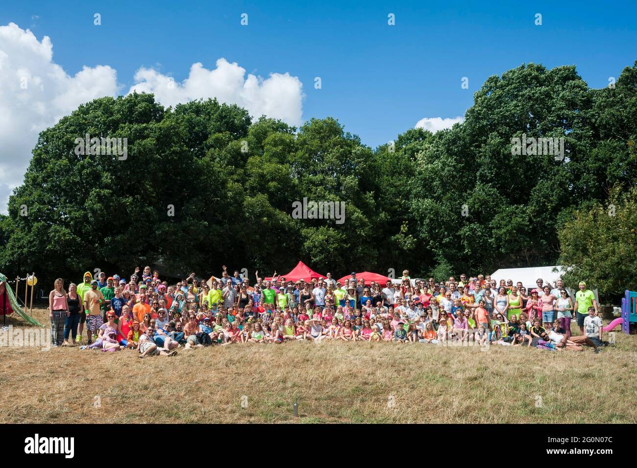 Lots and lots of people outside posed for a big group shot at a summer neon family festival. Stock Photo