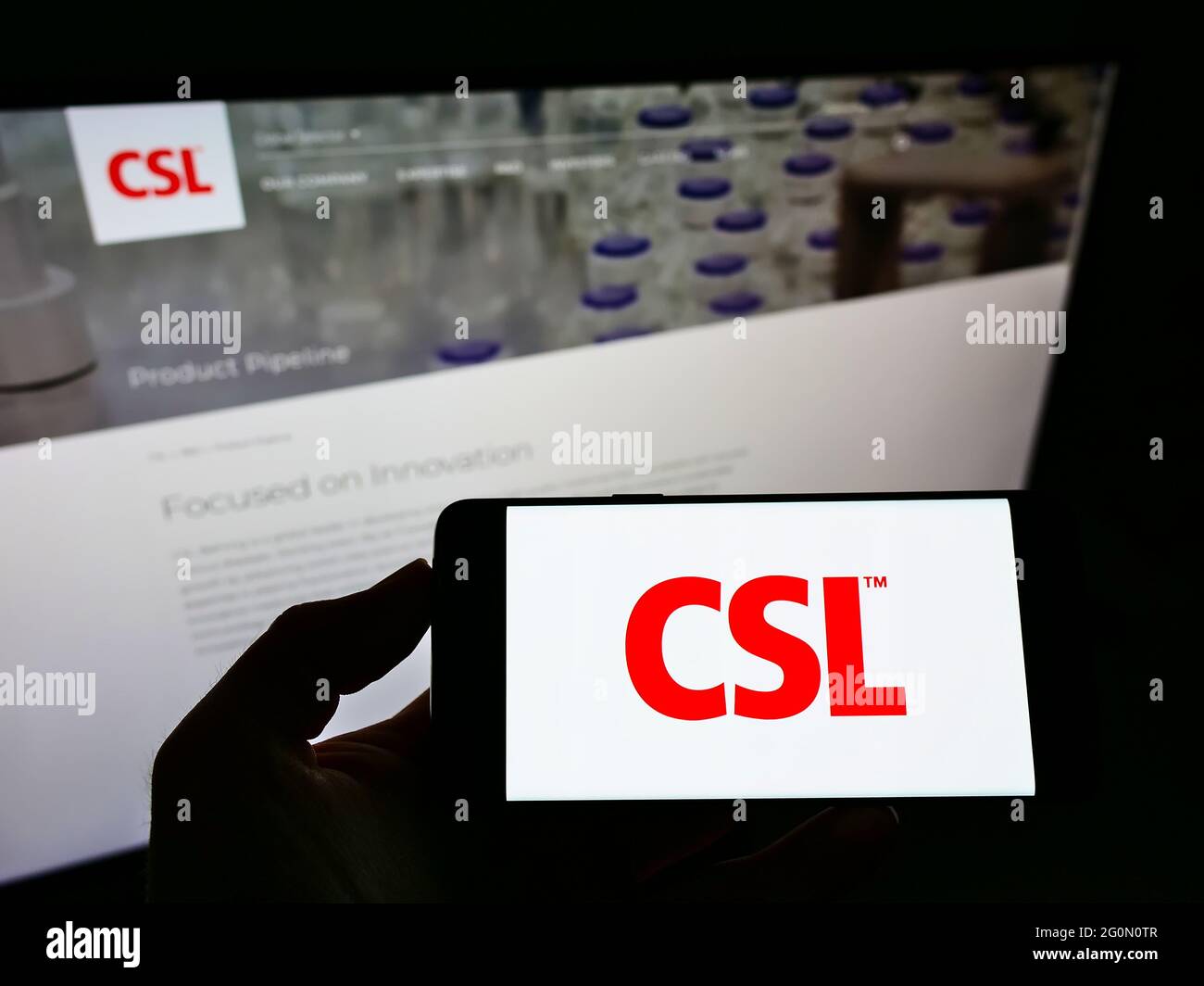 Person holding smartphone with logo of Australian pharmaceuticals company CSL Limited on screen in front of website. Focus on phone display. Stock Photo