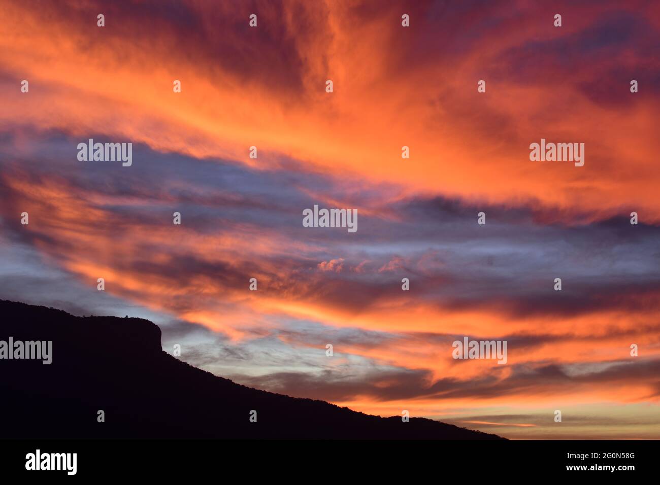 Sunset of orange and pink clouds with mountain silhouette Stock Photo ...
