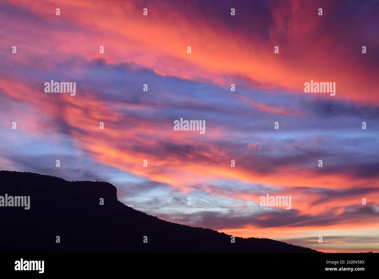 Sunset of orange and pink clouds with mountain silhouette Stock Photo ...
