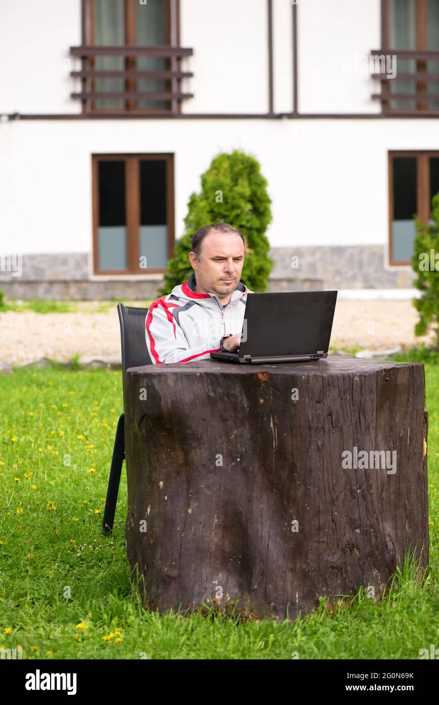 Man working in nature with laptop on a big stump Stock Photo