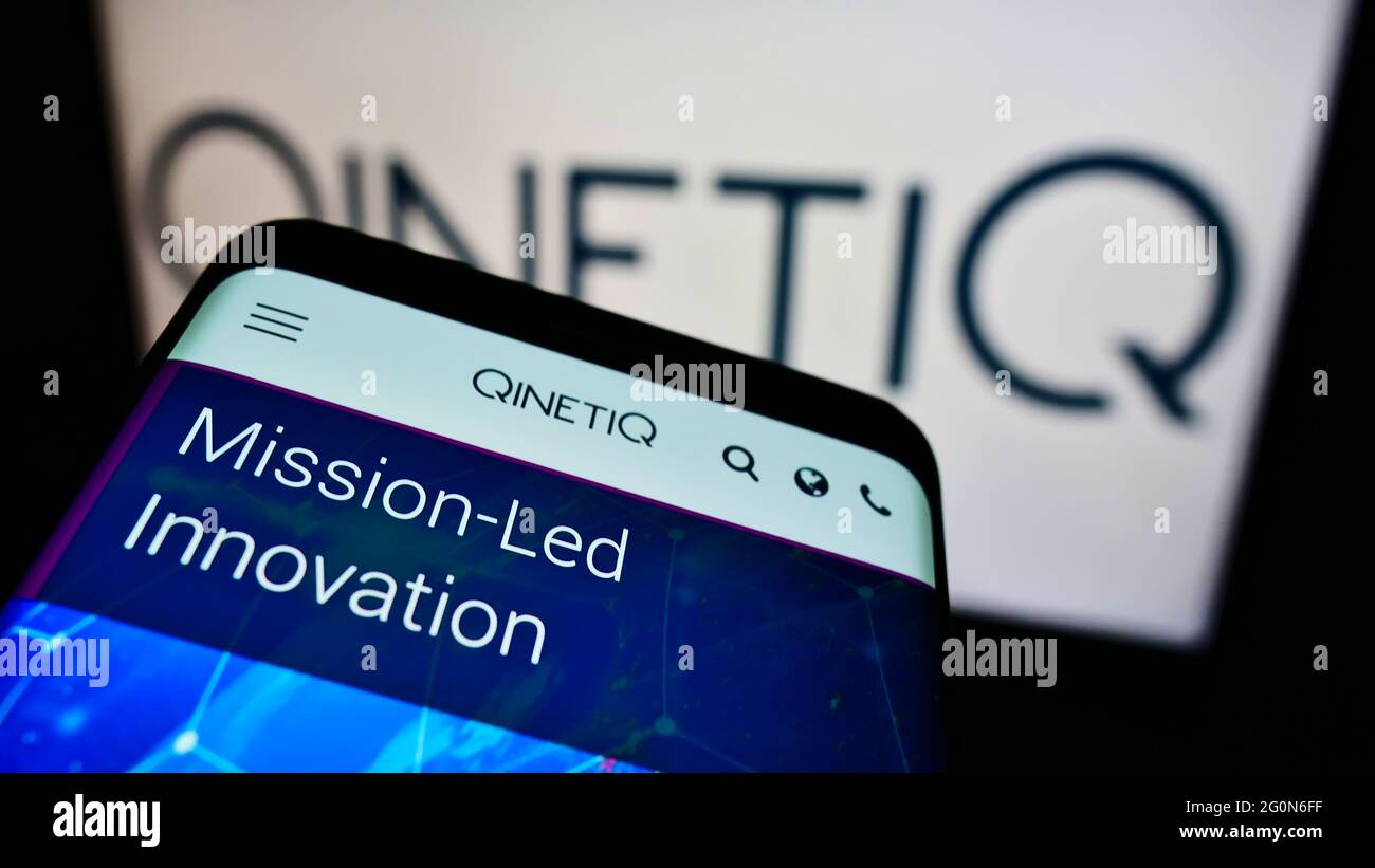 Mobile phone with website of British defence technology company QinetiQ Group plc on screen in front of logo. Focus on top-left of phone display. Stock Photo