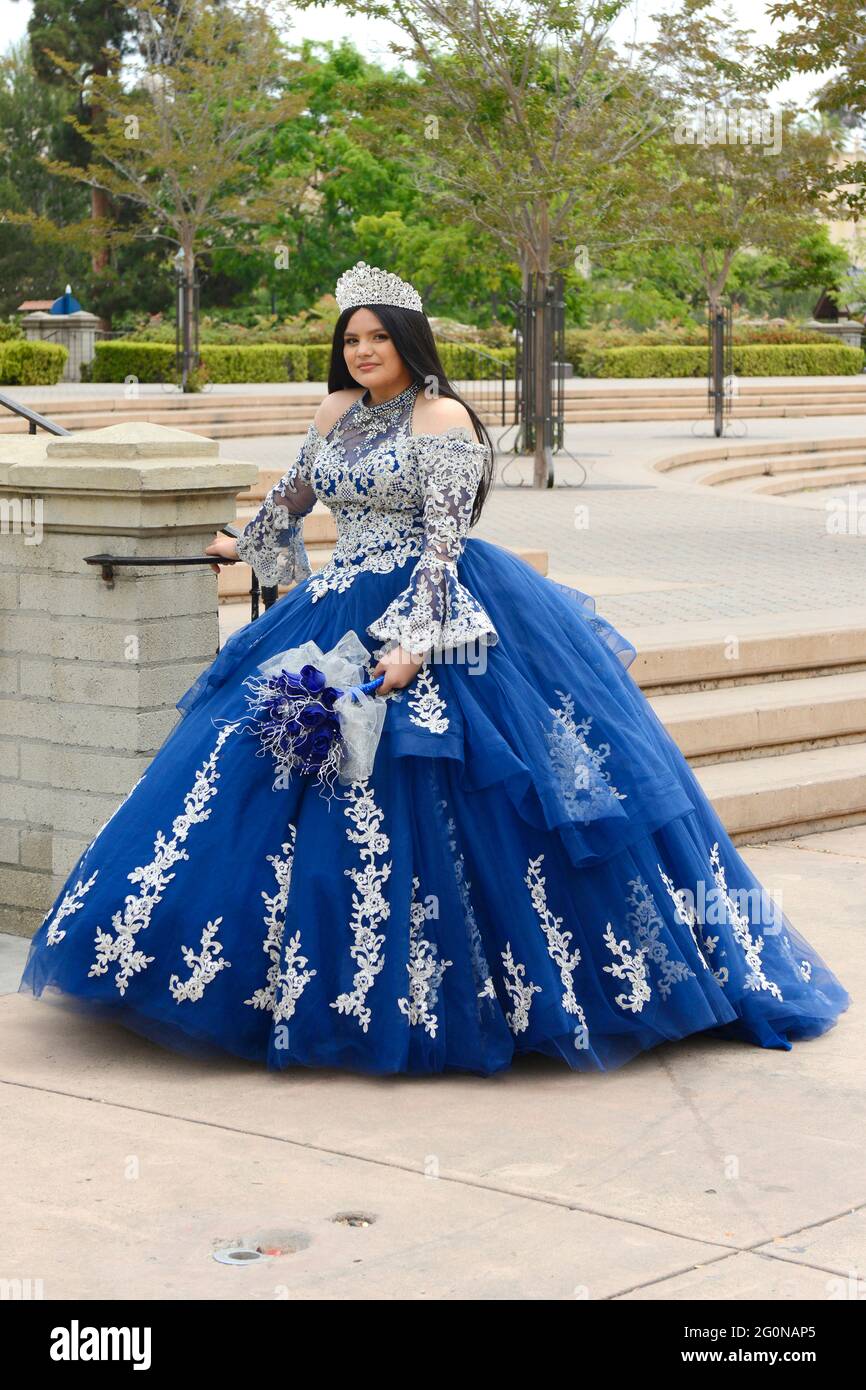 Young Mexican girl dressed in her Quinceanera dress waiting for a photographer at Balboa Park in San Diego CA Stock Photo