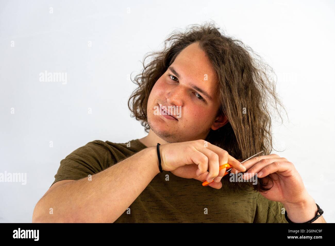 Young smiling guy is about to cuthair with scissors Stock Photo