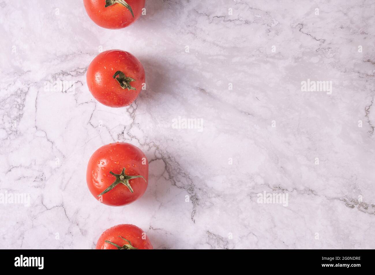Line of tomatoes on composition on a marble table. Stock Photo
