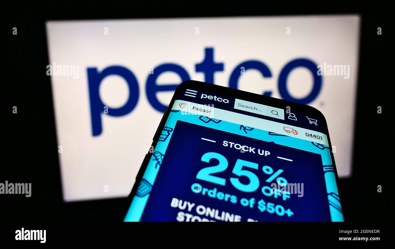 Cellphone with webpage of US retailer Petco Health and Wellness Company Inc. on screen in front of company logo. Focus on top-left of phone display. Stock Photo