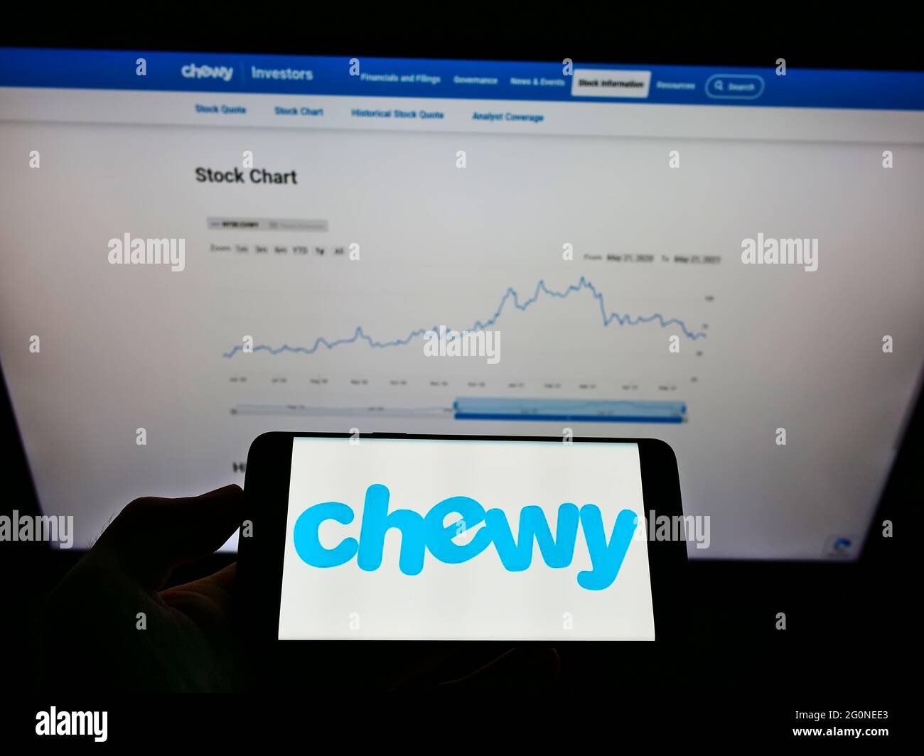 Person holding smartphone with logo of US pet food online retail company Chewy Inc. on screen in front of website. Focus on phone display. Stock Photo