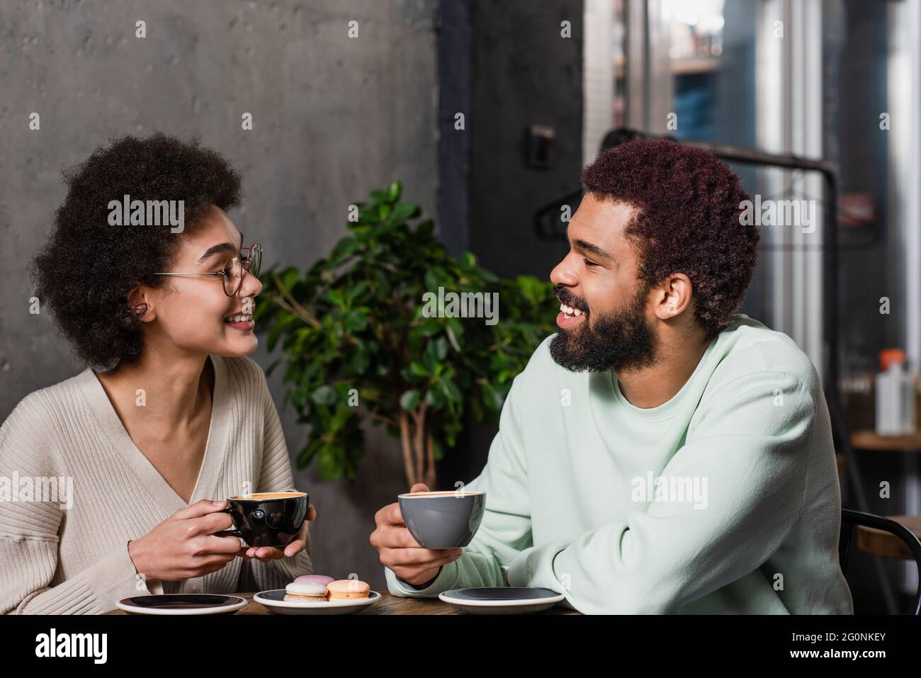 Side view of smiling african american couple holding coffee near ...