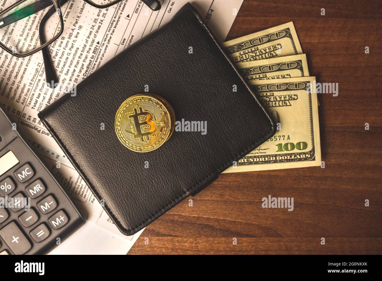 Filling the tax forms with bitcoin crypto currency coin money, black  leather wallet with dollars and calculator on a wooden table, top view  Stock Photo - Alamy