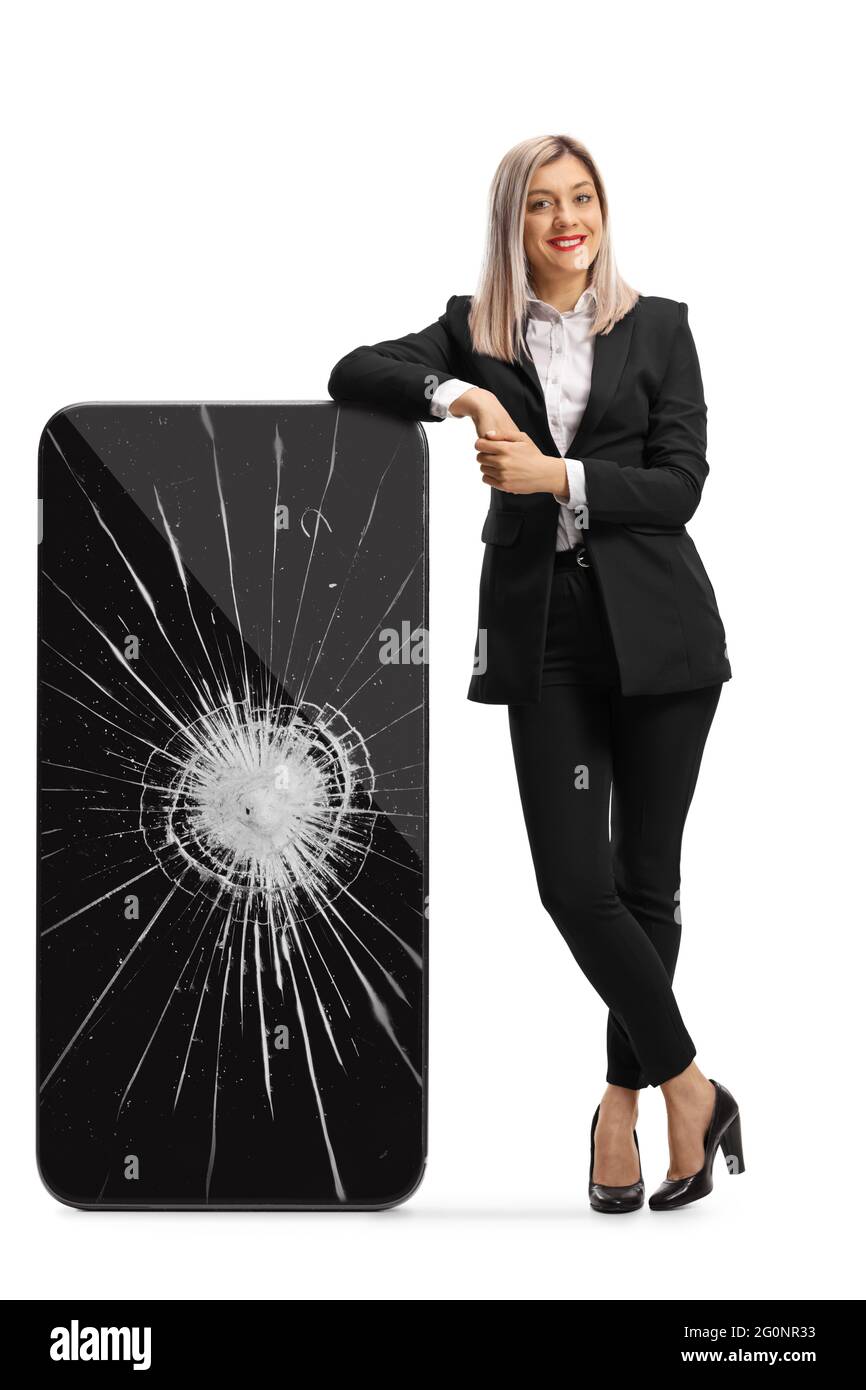 Full length portrait of a young businesswoman leaning on a smartphone with a cracked screen isolated on white background Stock Photo