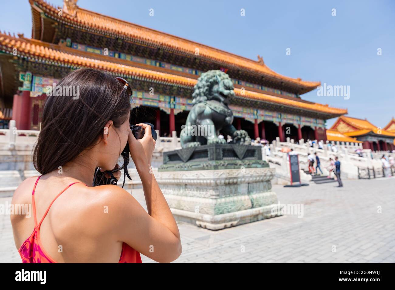 Tourist photographer taking pictures with camera of sculpture in front of ancient chinese temple, china. Asia summer travel, tourism destination Stock Photo