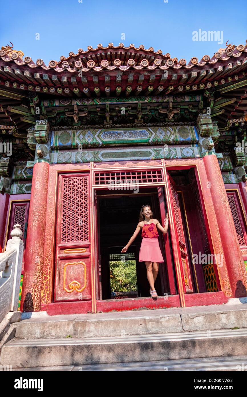 Asian caucasian woman visiting old chinese temple walking through traditional entrance door on summer holiday. china travel destination. Multiracial Stock Photo