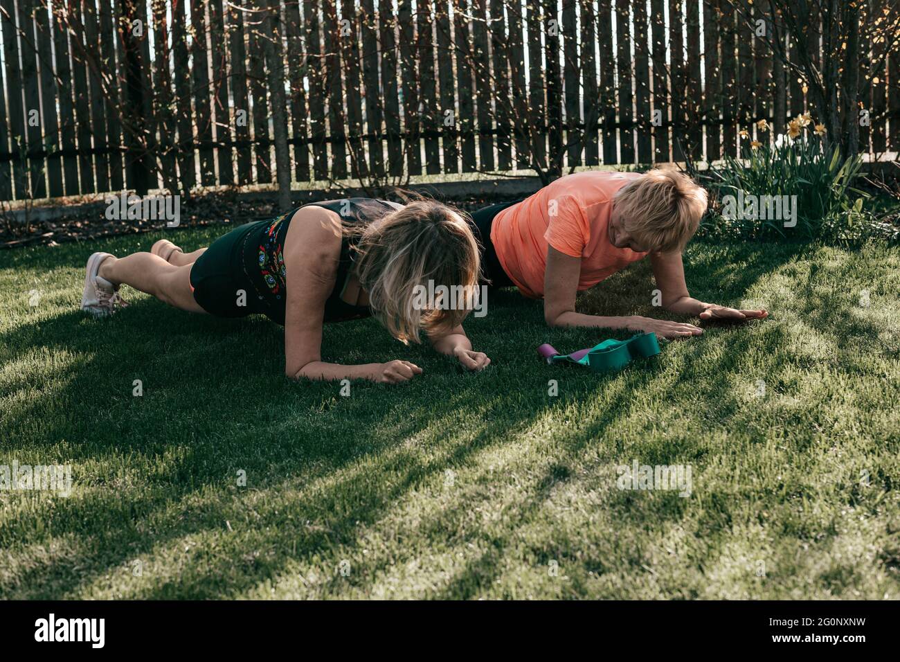 Active senior 55-59 years women perform exercises in the rays of the sun outdoors, plank position Stock Photo
