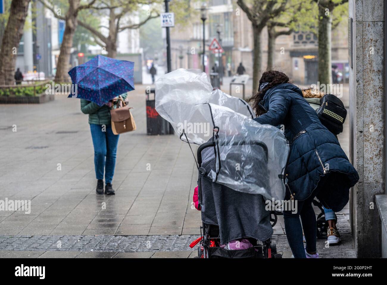 Rainy weather, rain shower, storm, a mother tries to cover the pram with a rain cover, spontaneous heavy rain shower, Kettwiger Strasse, downtown Esse Stock Photo