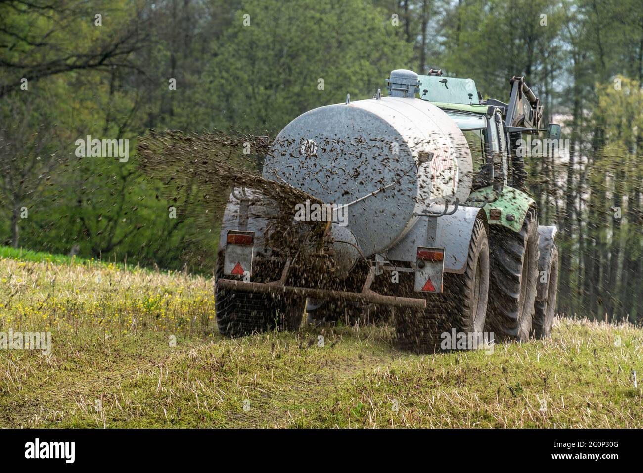 liquid manure is spread on a field with a tractor from a liquid manure barrel to fertilise the farmland nrw germany 2G0P30G