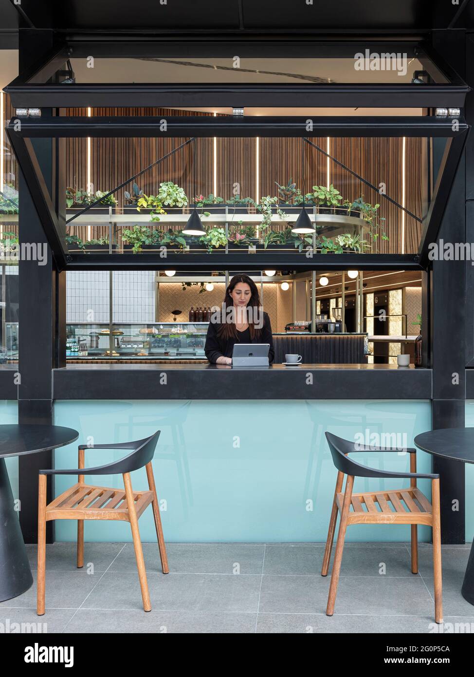 Cafe outdoor seating area looking into lobby through feature operable windows. 65 Pirrama Road, Pyrmont, Australia. Architect: Gray Puksand, 2021. Stock Photo