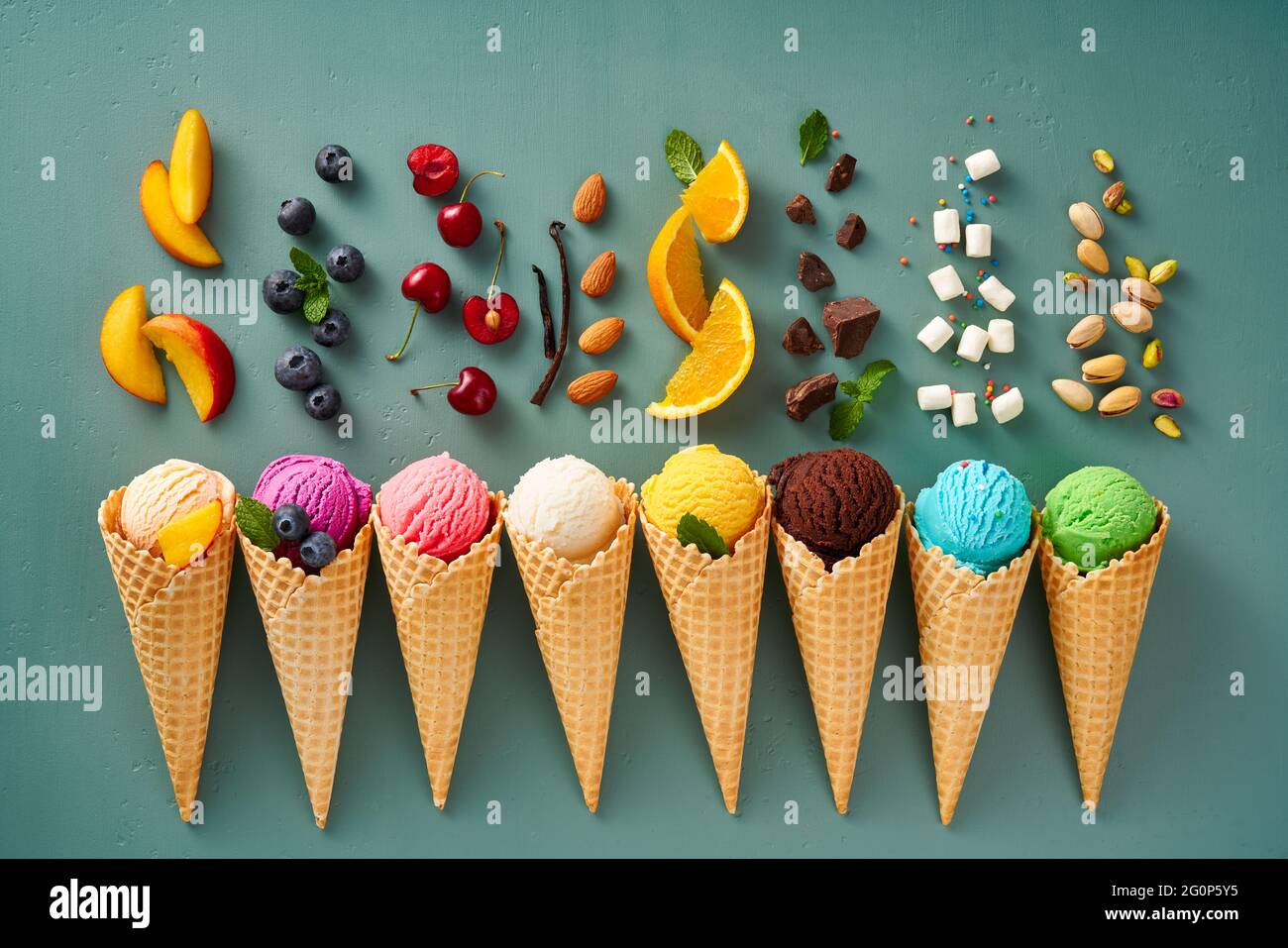 Assorted of ice cream in cones on blue background. Colorful set of ice cream of different flavours. Ice cream isolated with nuts, fruits and berries. Stock Photo