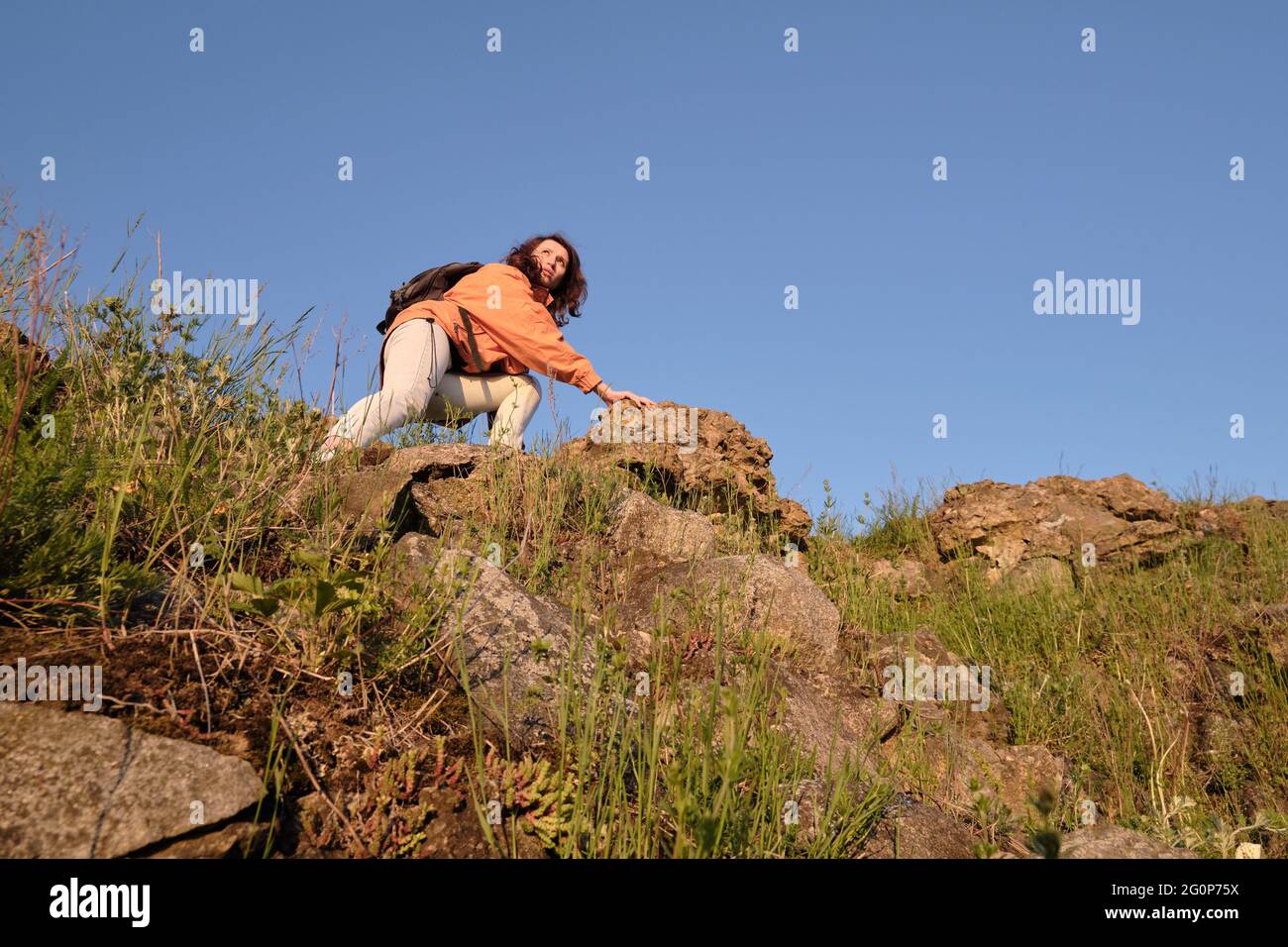 The girl climbs a rocky mountain. Travel outside the city alone. Stock Photo