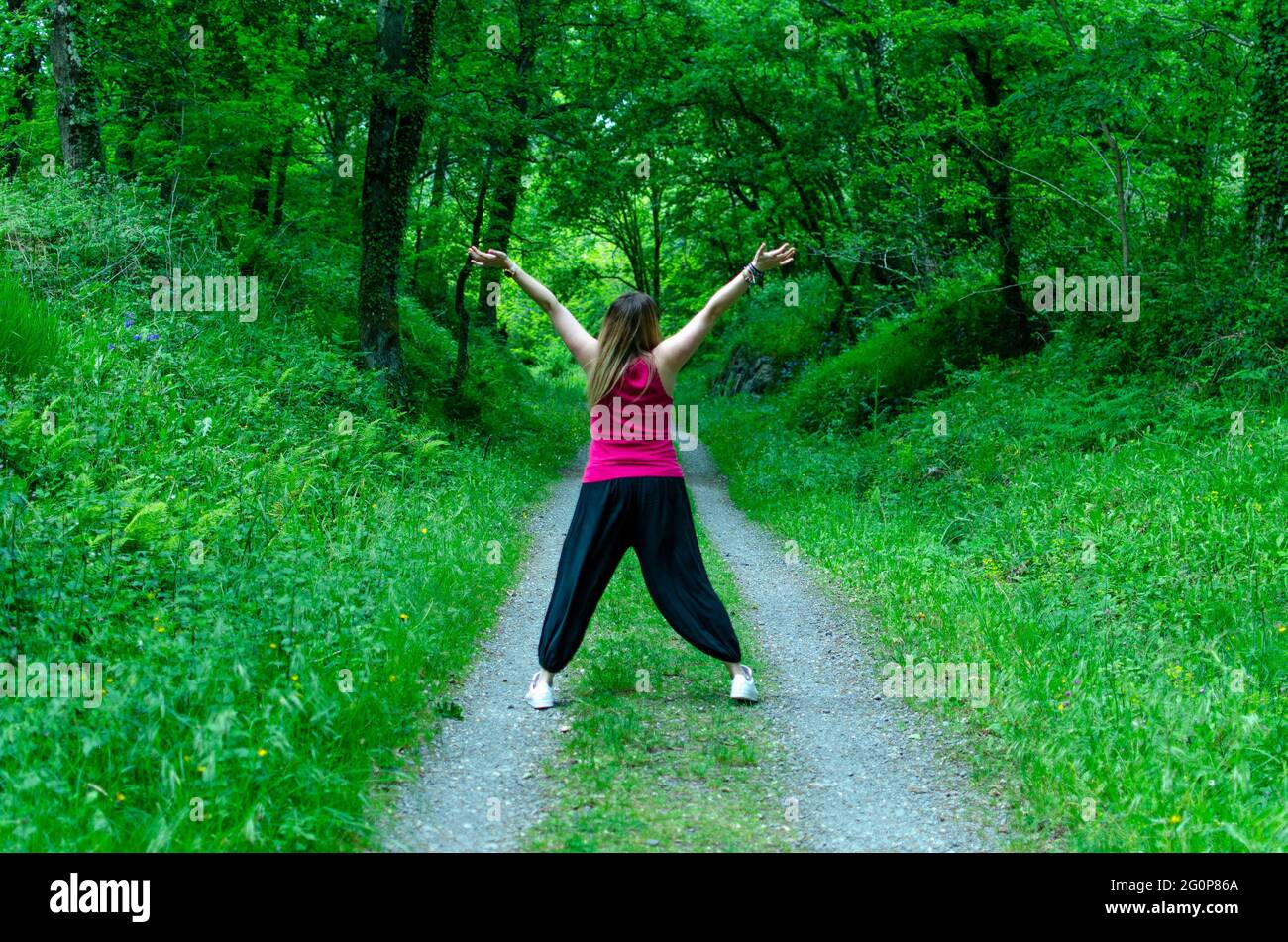 Excited female with raised arms on a pathway in a green forest Stock ...
