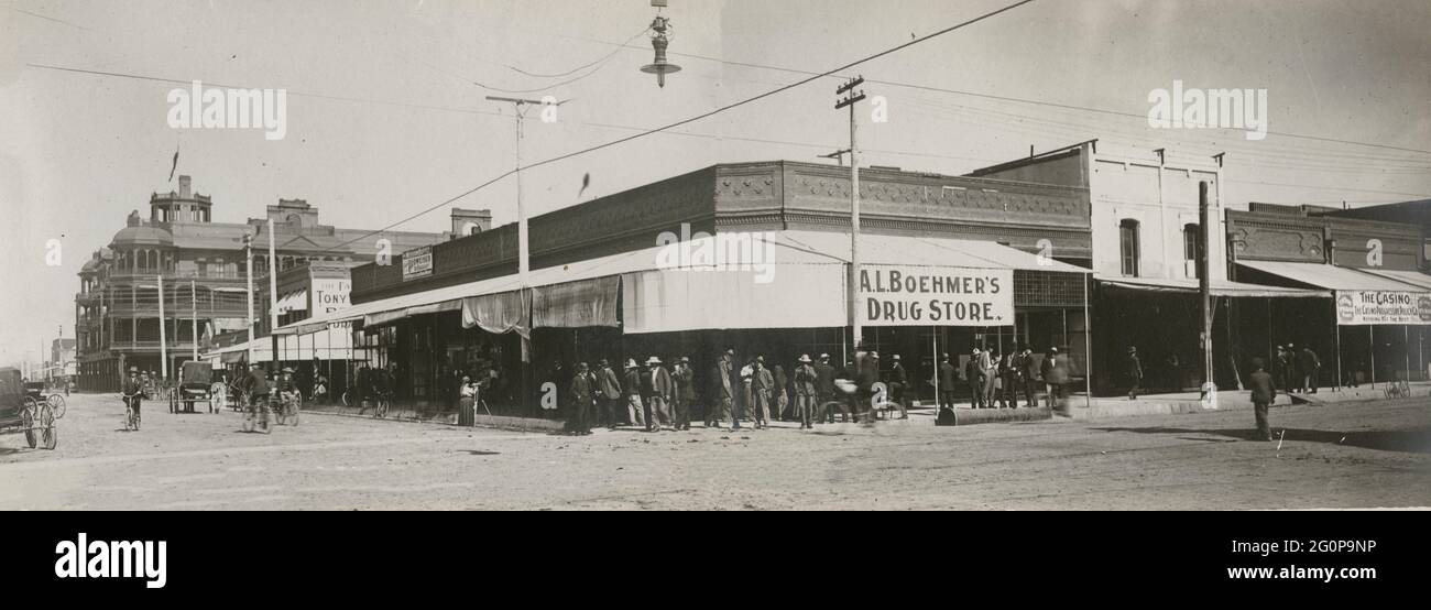 The busy corner of Phoenix, Arizona - Postcard shows an intersection of a street in Phoenix, Arizona with men standing in front of A.L. Boehmer's Drug Store. Men are on bicycles and a sole female figure stands on the side of the street with a tripod, 1907 Stock Photo