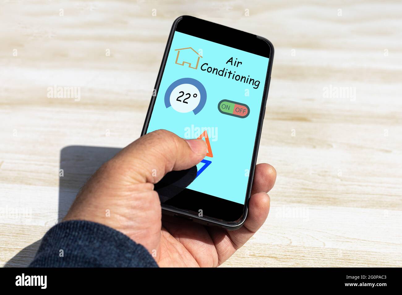 person using an application on the mobile phone to control the air conditioner at home where you see the degrees and the keys to raise and lower the t Stock Photo