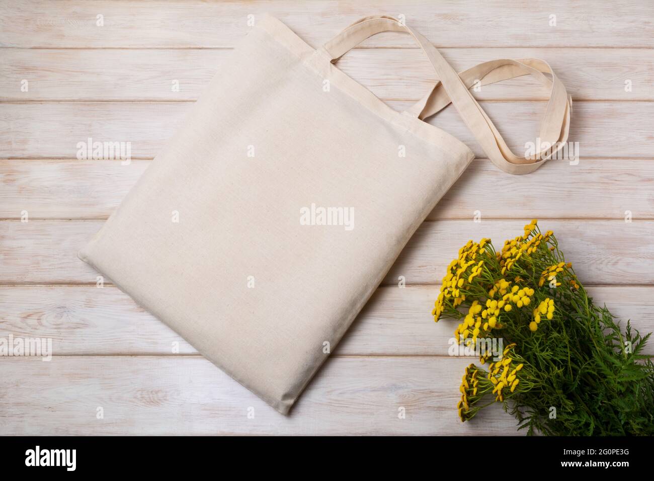 Canvas tote bag mockup with yellow wild flowers. Rustic linen shopper bag mock up for branding presentation Stock Photo