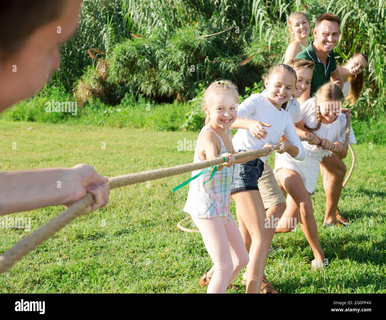 people with kids having fun outdoors pulling rope Stock Photo