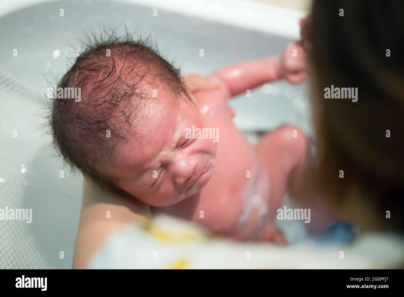 Mother bathing baby boy in white bathroom, Two week old Stock Photo Alamy