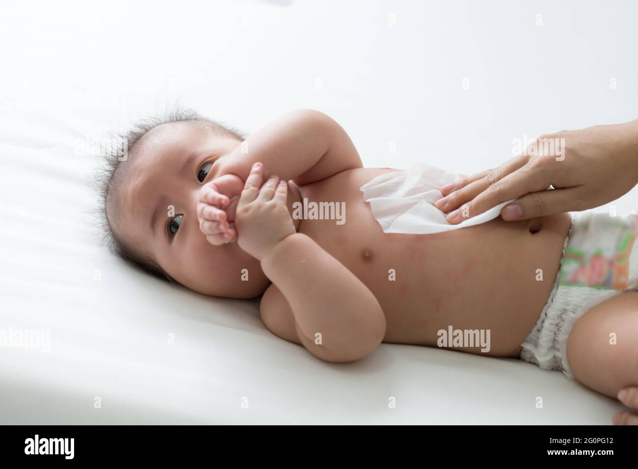 Mom cleaning up and wipe body baby by wet tissue when changing nappies ...