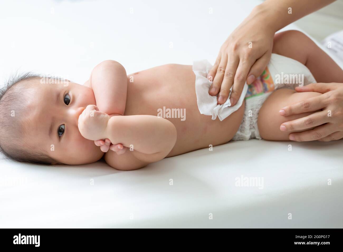 Mom cleaning up and wipe body baby by wet tissue when changing nappies ...