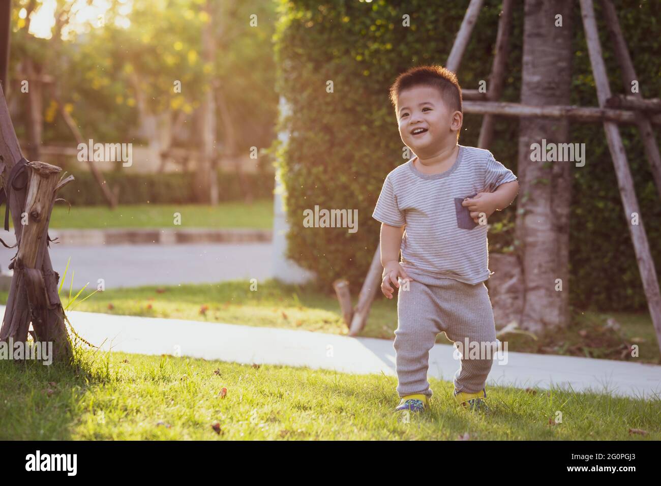 Asian baby boy running in the garden during the evening, with the sun shining from the back of the child Stock Photo