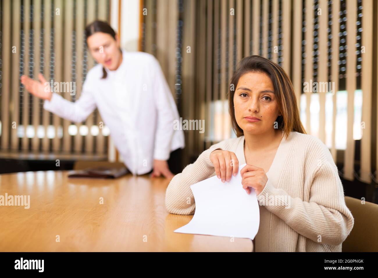 Unhappy woman standing in office after reprimand from chief Stock Photo