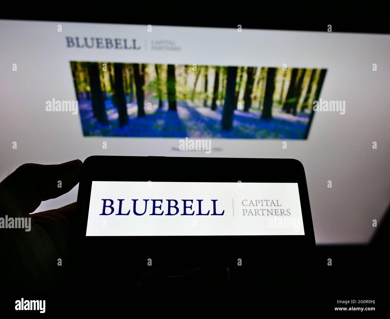 Person holding smartphone with logo of British investor Bluebell Capital  Partners Limited on screen in front of website. Focus on phone display  Stock Photo - Alamy