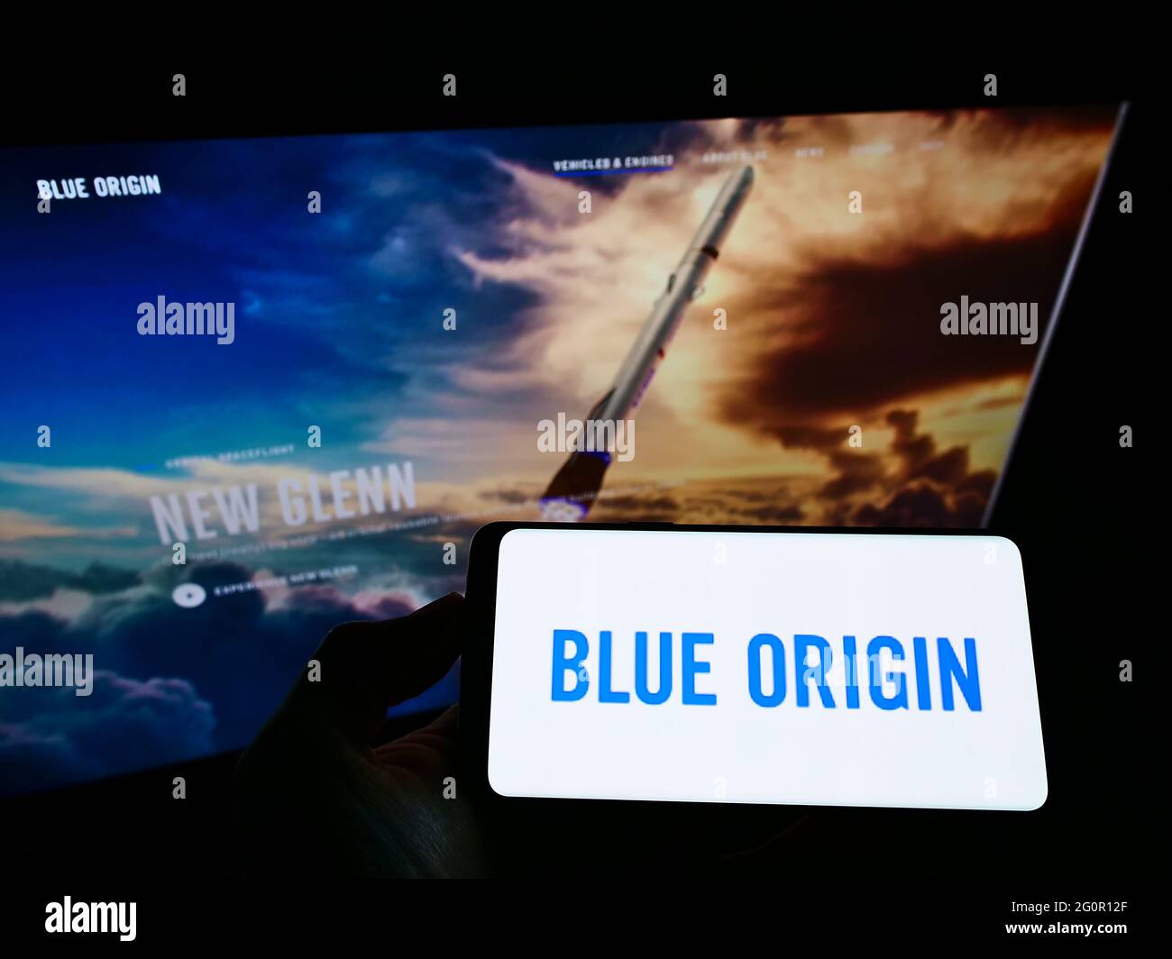Person holding smartphone with logo of US aerospace company Blue Origin LLC on screen in front of website. Focus on phone display. Stock Photo