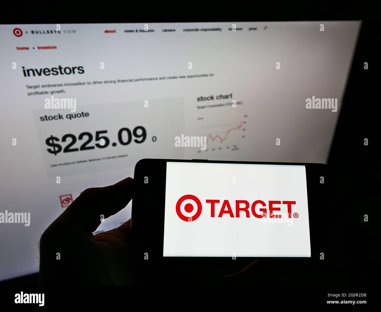 Person holding smartphone with logo of US retail company Target Corporation on screen in front of website. Focus on phone display. Stock Photo