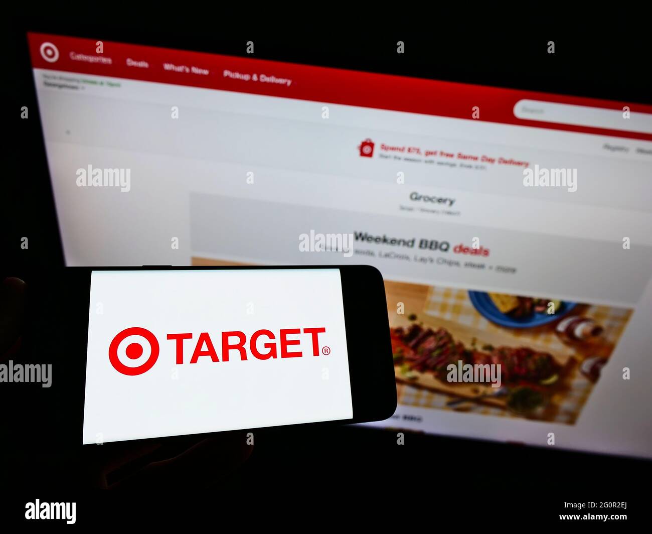 Person holding smartphone with business logo of American retail company Target Corporation on screen in front of website. Focus on phone display. Stock Photo