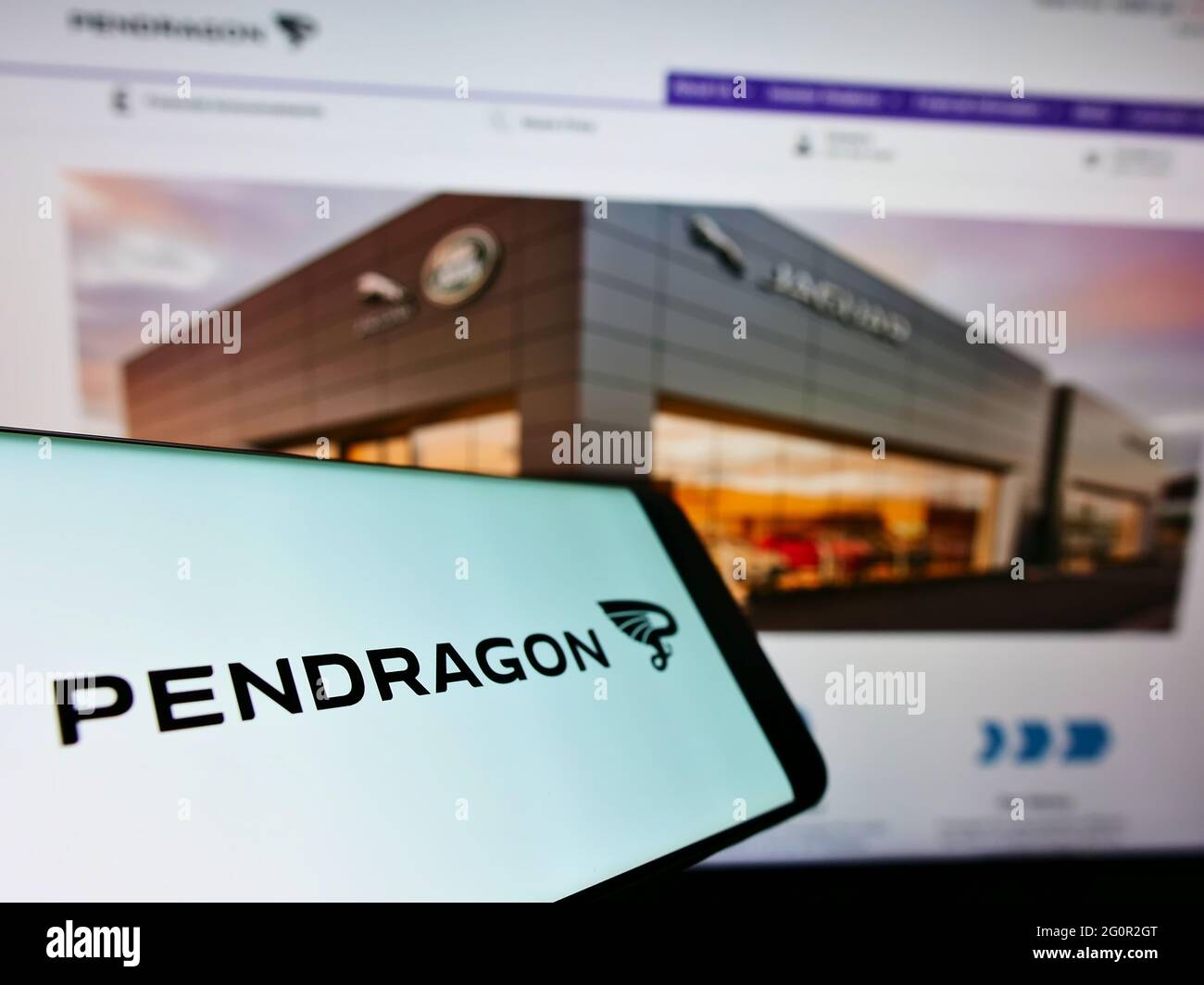 Smartphone with logo of British automotive retail company Pendragon PLC on screen in front of website. Focus on center-left of phone display. Stock Photo