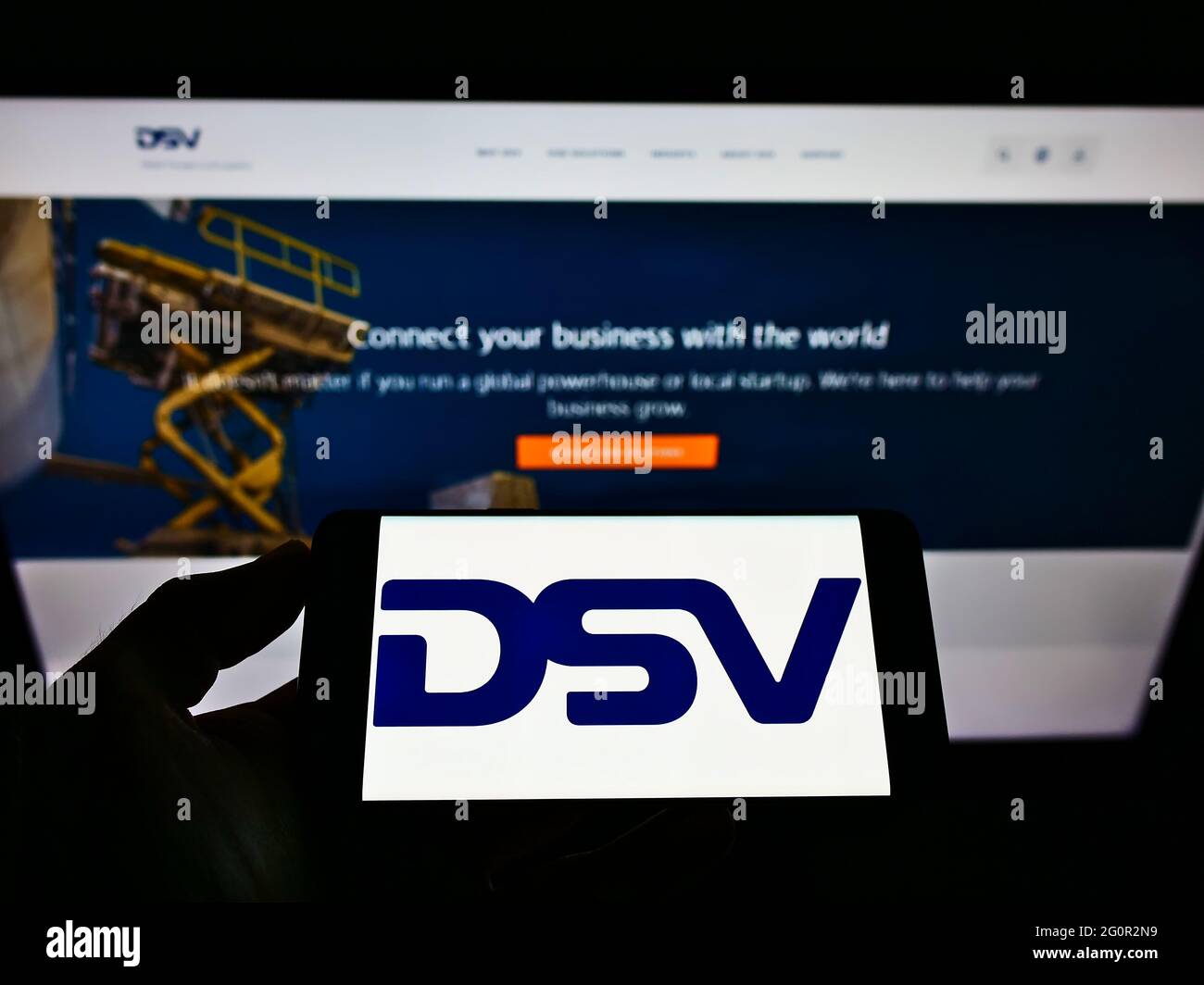 Person holding smartphone with logo of Danish logistics company DSV Panalpina AS on screen in front of website. Focus on phone display. Stock Photo