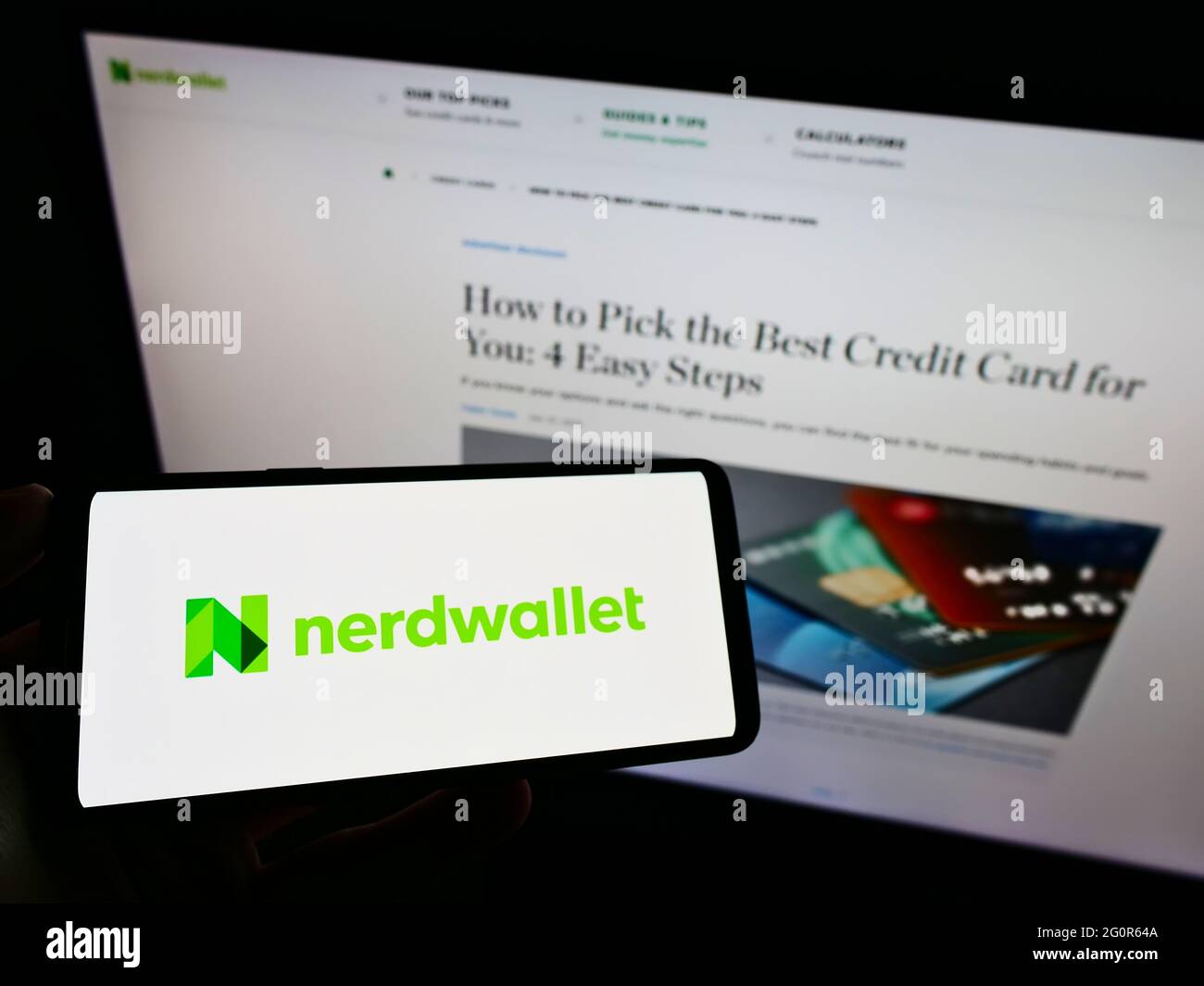 Person holding cellphone with logo of US personal finance company NerdWallet Inc. on screen in front of business website. Focus on phone display. Stock Photo