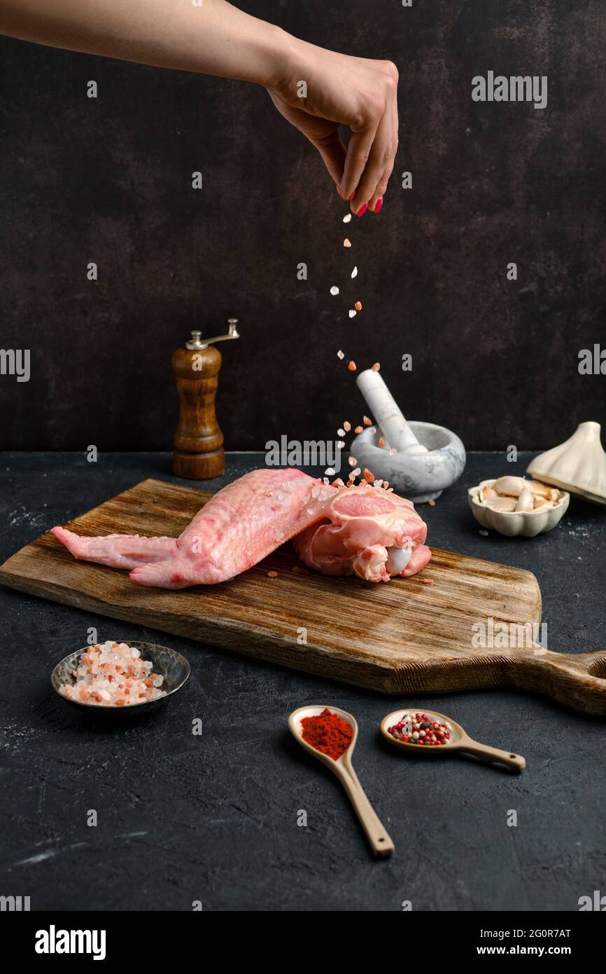 Female hand seasoning with salt raw turkey wing Stock Photo Alamy