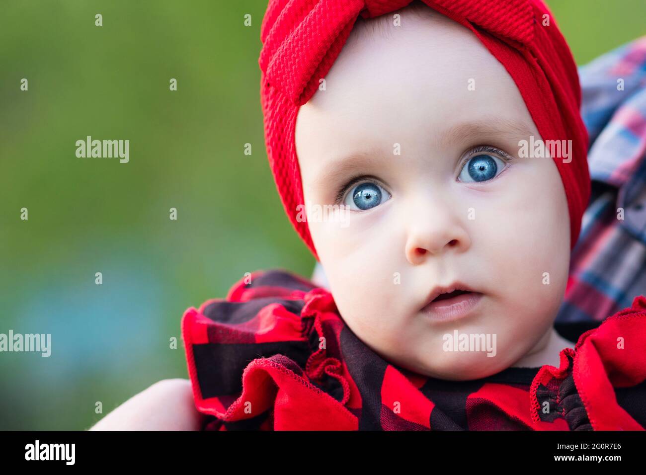 Adorable little baby on nature background. Close up portrait cute portrait  of blue-eyed toddler girl on walk in arms of parent Stock Photo - Alamy