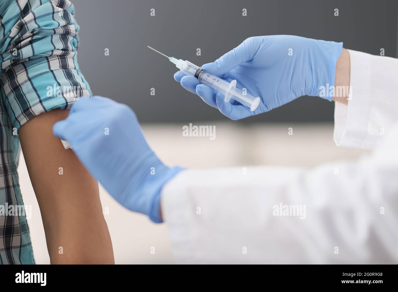 Nurse making injection of medicine into patient shoulder in clinic ...