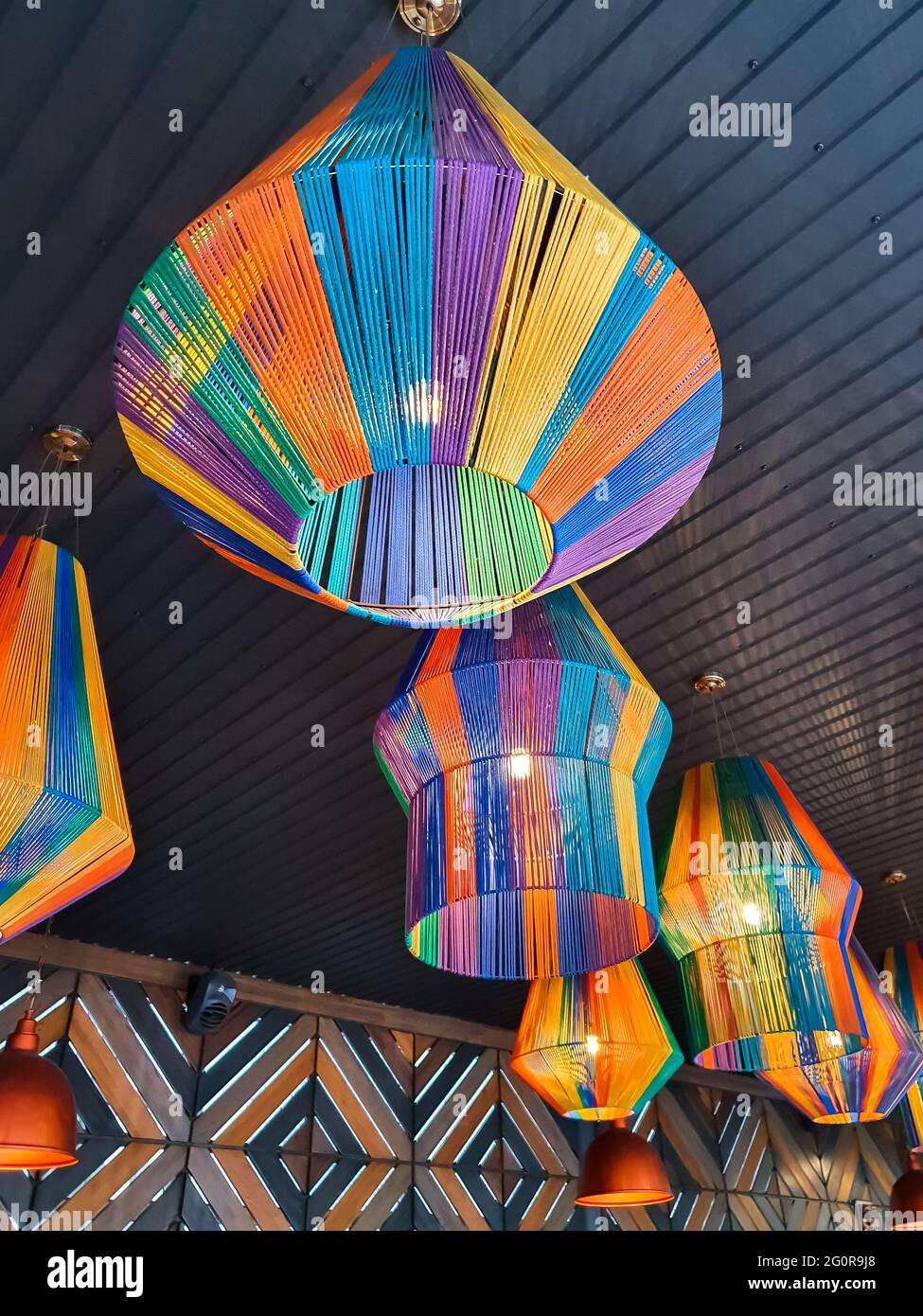 Chandeliers made of colorful threads in the form of a lantern under the ceiling. Restaurant illumination, cafe decoration in the form of multicolor la Stock Photo