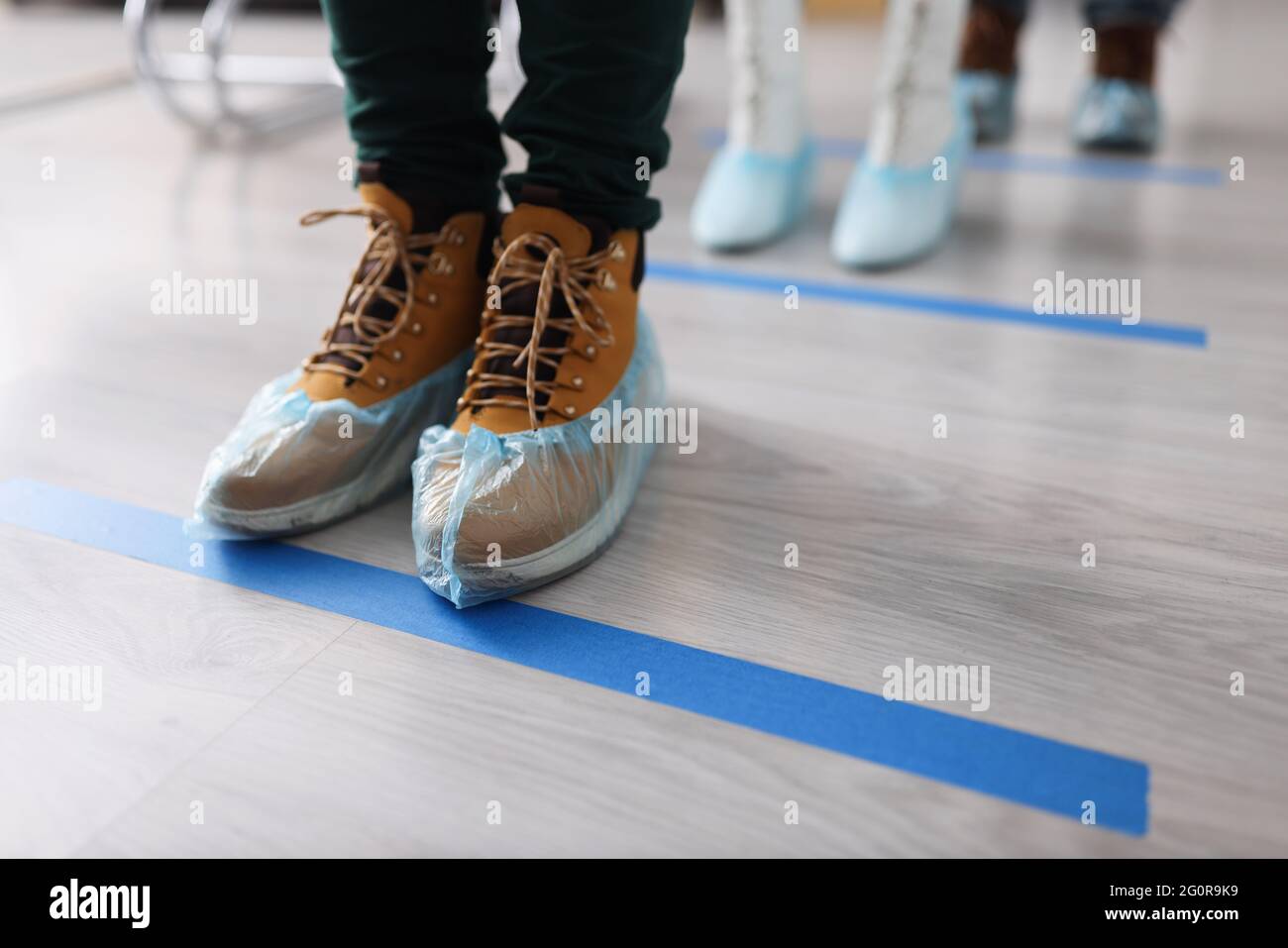 People in shoe covers on their feet standing in line near blue line