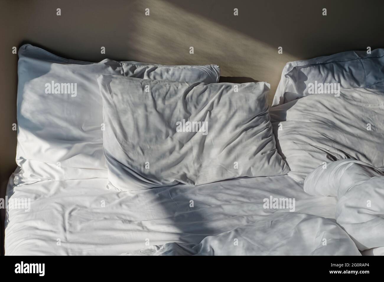 Unmade messy bed with white bedsheet Stock Photo