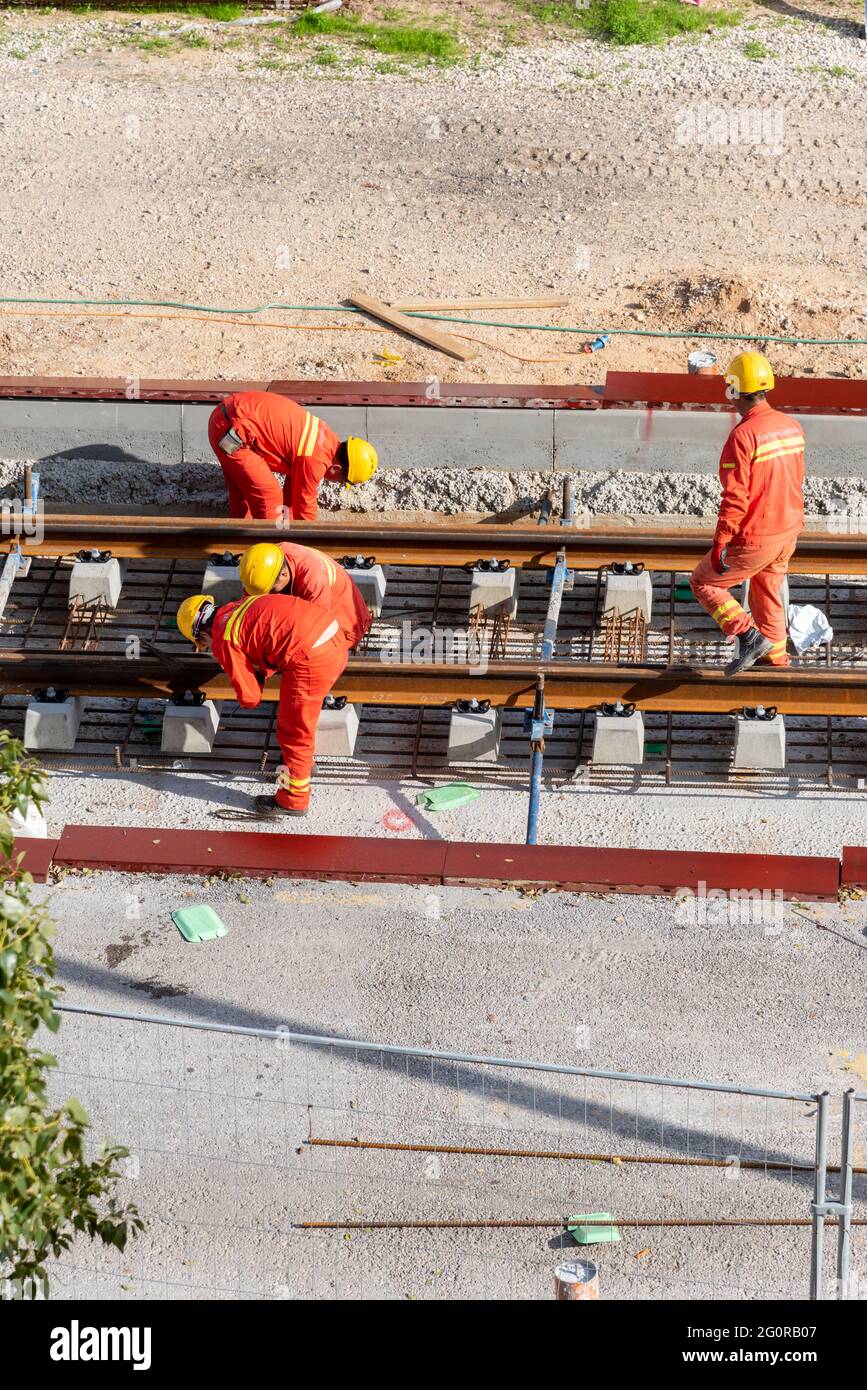 Tel Aviv, Israel - May 20 2021: Construction Workers with Orange overalls. Light rail tracks. blue collar worker. Concept Collaboration teamwork. Trucks, concrete mixer, bulldozer. High quality photo Stock Photo